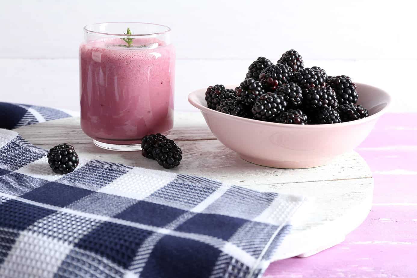 Delicious berry smoothie with blackberries on table close up