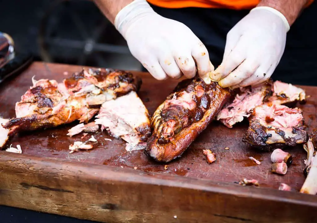 Chef Hands cleaning Grilled spare beef or pork back ribs prepared in smoker.