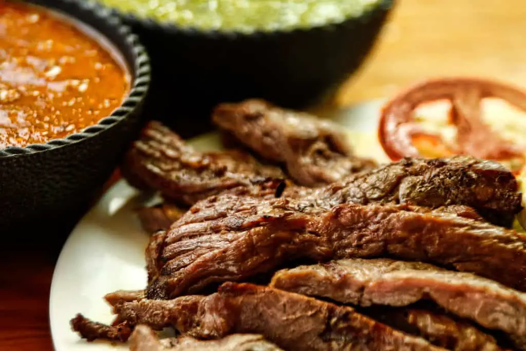 Beef fajitas on a white plate with sauces