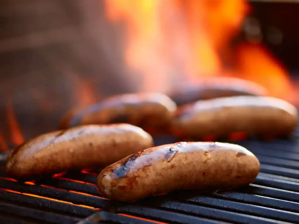 grilling bratwurst sausages over flaming grill
